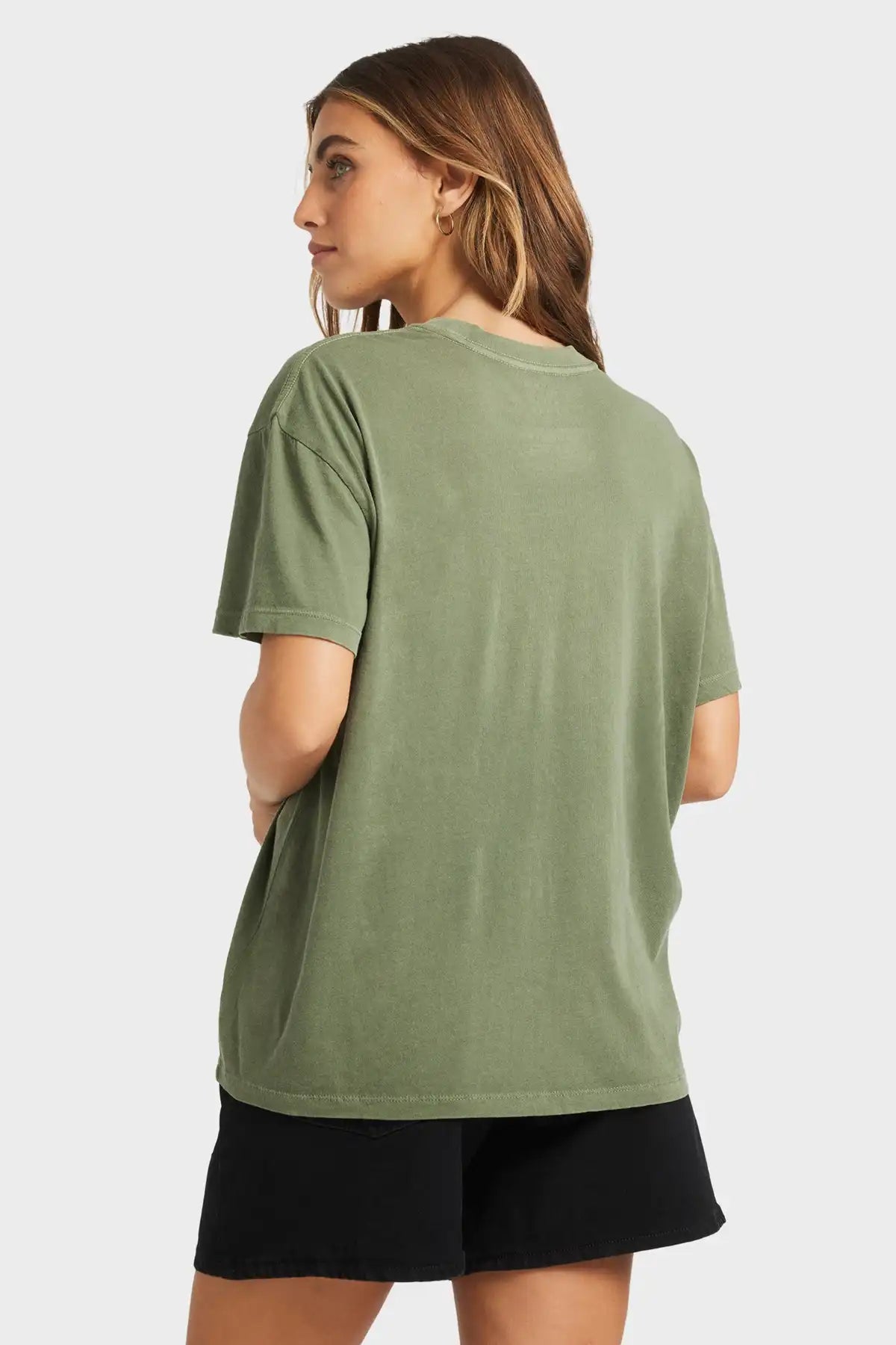Woman wearing a Billabong green t-shirt and black shorts on a white background