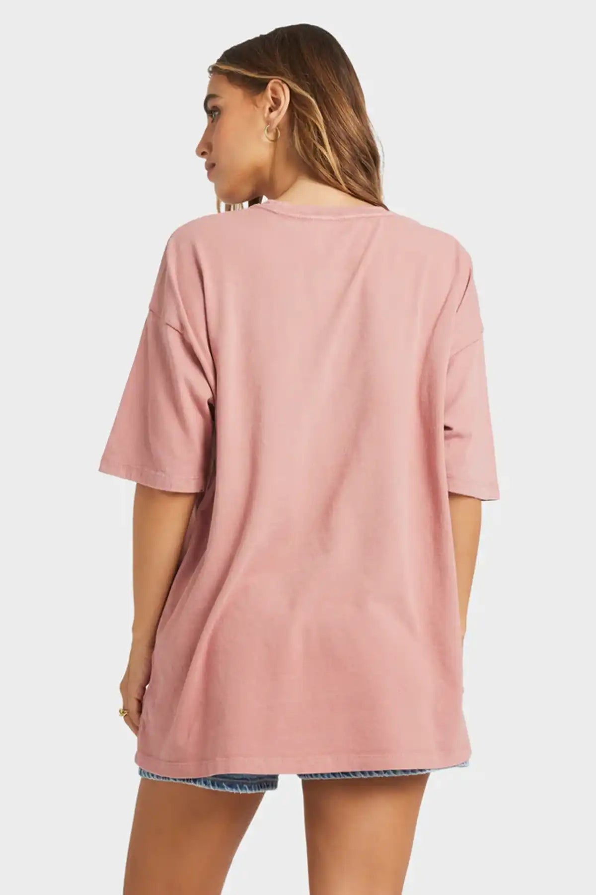 Person wearing a pink Billabong oversized t-shirt on a white background