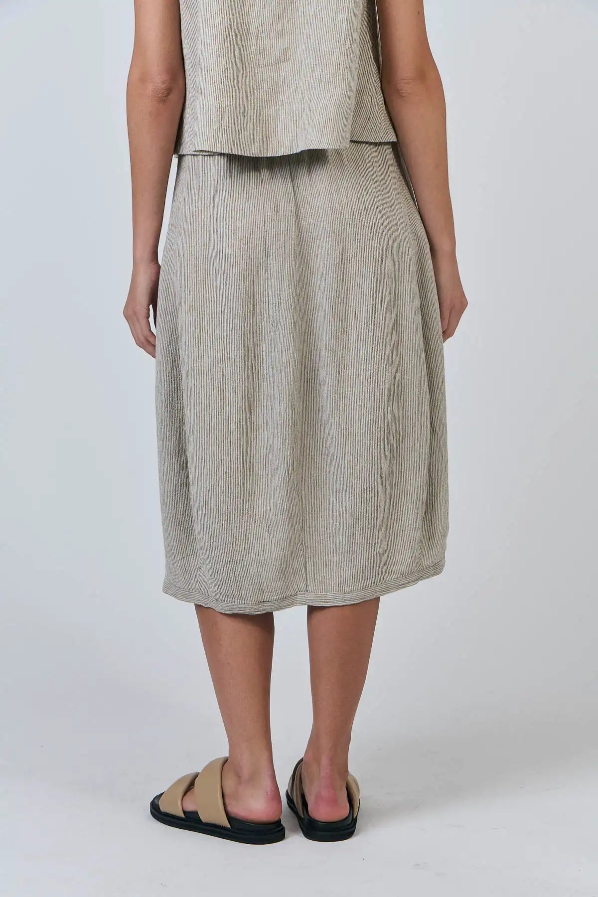 Person wearing a beige sleeveless top and Blister Stripe Linen Skirt set on a white background back view hands by side