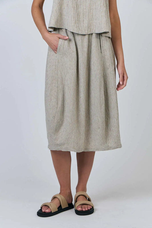 Person wearing a beige sleeveless top and Blister Stripe Linen Skirt set on a white background front view with hand in pocket