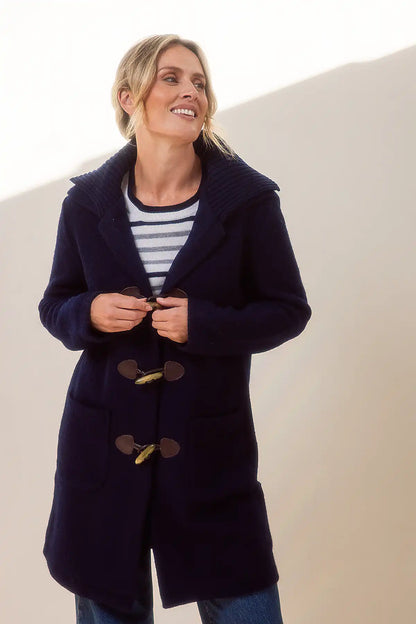Woman wearing a navy blue boiled wool duffle coat with a white background