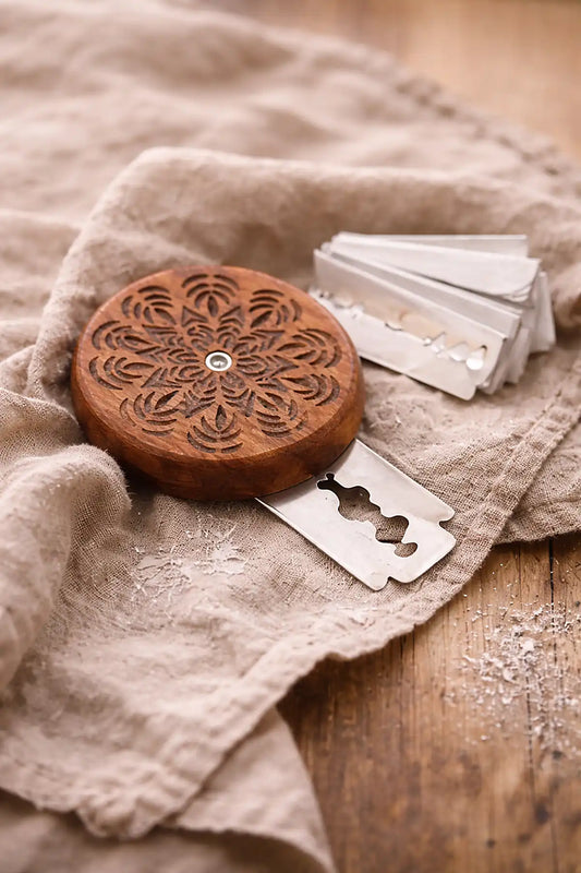 Wooden bread lame with intricate design on a textured fabric surface
