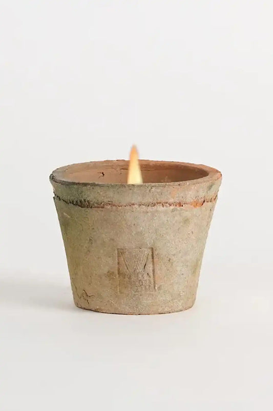 Ceramic candle holder with a lit candle on a white background