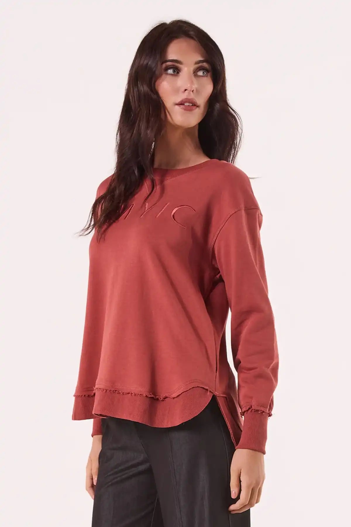 Woman wearing a Chille Everyday Wander Pullover in Rust with embroidery logo on a white background side view