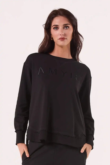 Woman wearing a Chille Everyday Wander Pullover in Midnight Black with a logo on a white background front on view
