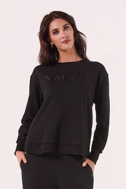 Woman wearing a Chille Everyday Wander Pullover in Midnight Black with 'AMYIC' branding on a white background front view