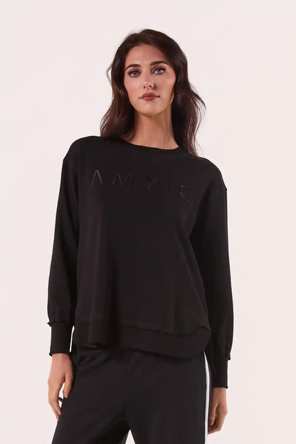 Woman wearing a Chille Everyday Wander Pullover in Midnight Black with text on a light pink backgroundfront view arms by side