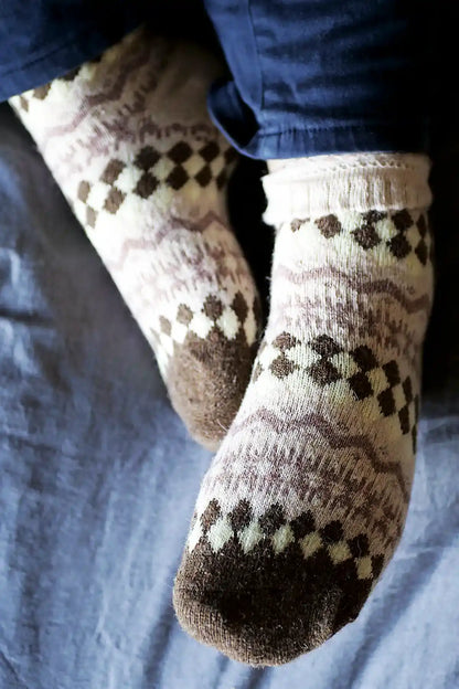 Patterned socks worn on a person's feet with a blue fabric background