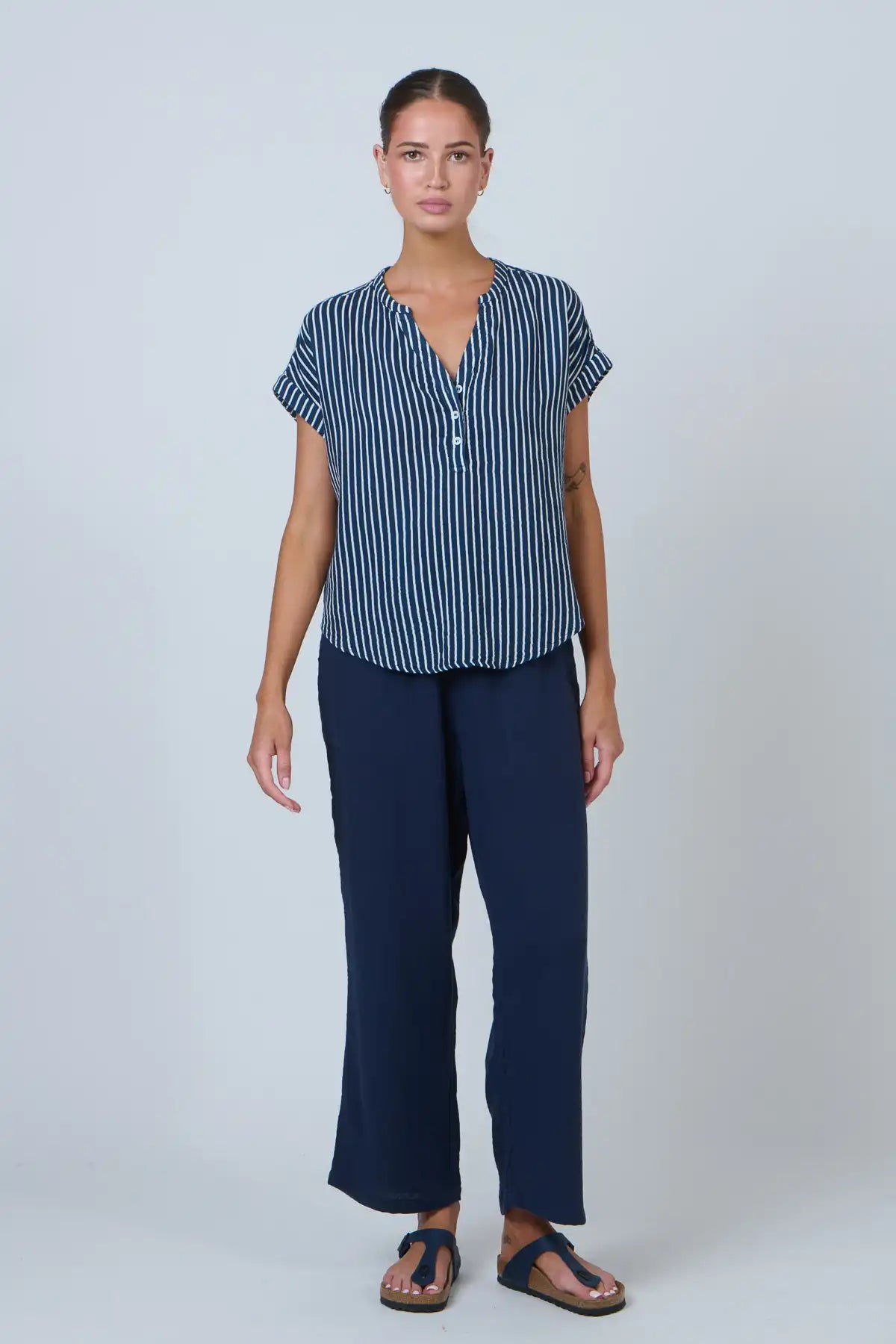 lady wearing the coastal navy and white strip cotton top and navy pants on a white background