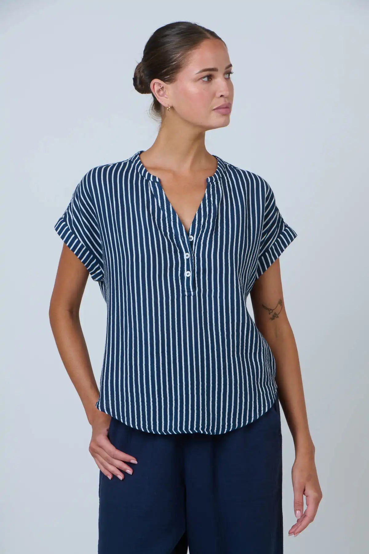 front view of lady wearing the coastal strip cotton top in navy and white on white background