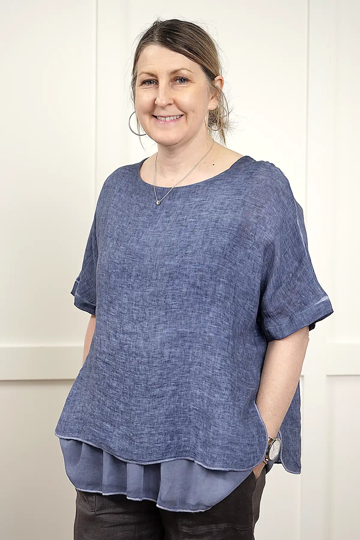 Woman wearing a Elena Linen Top in Denim standing side on against a white background
