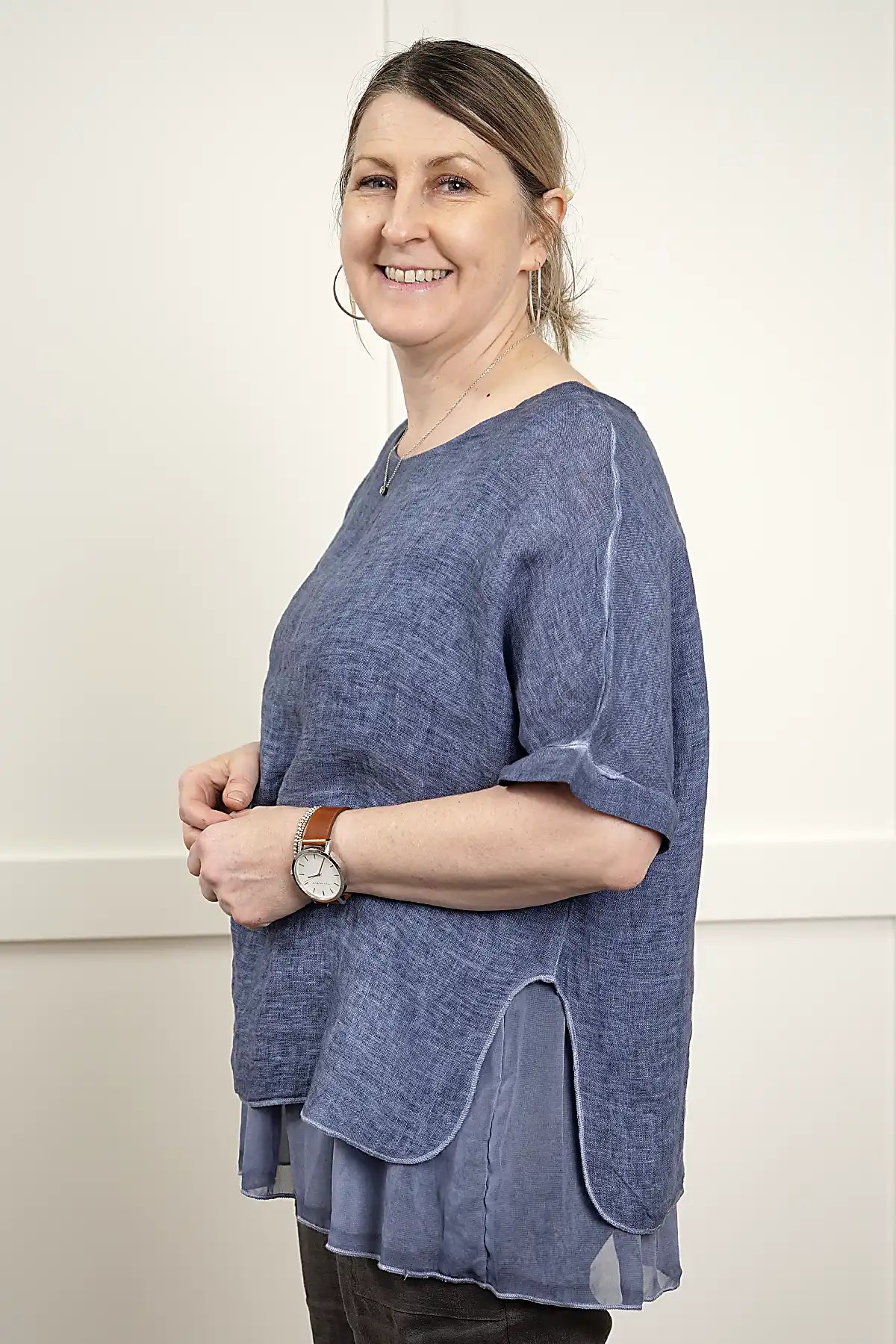 Woman wearing a Elena Linen Top in Denim standing side on  against a plain background