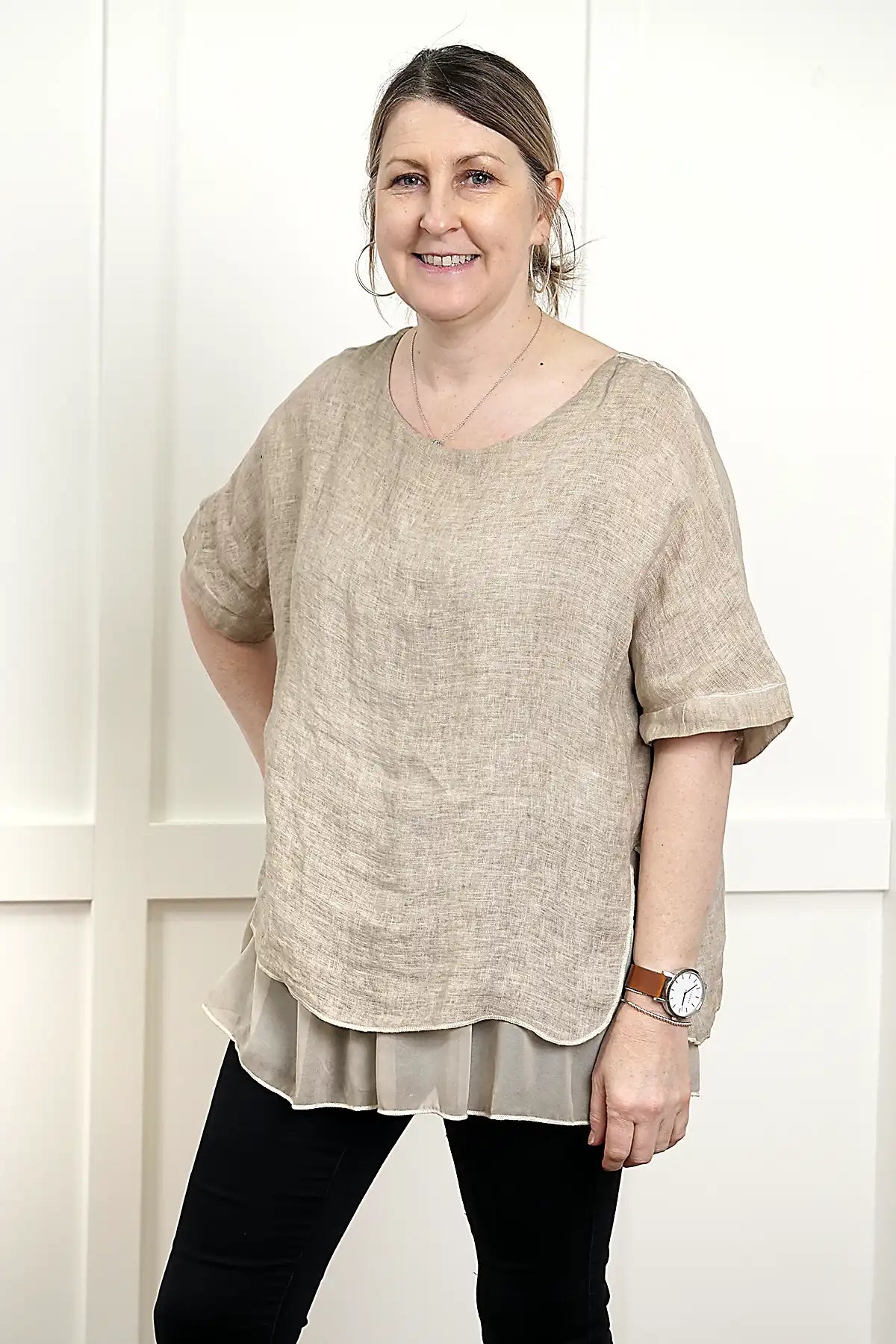woman wearing the Elena Linen Top in Latte 3/4 view standing against a white wall