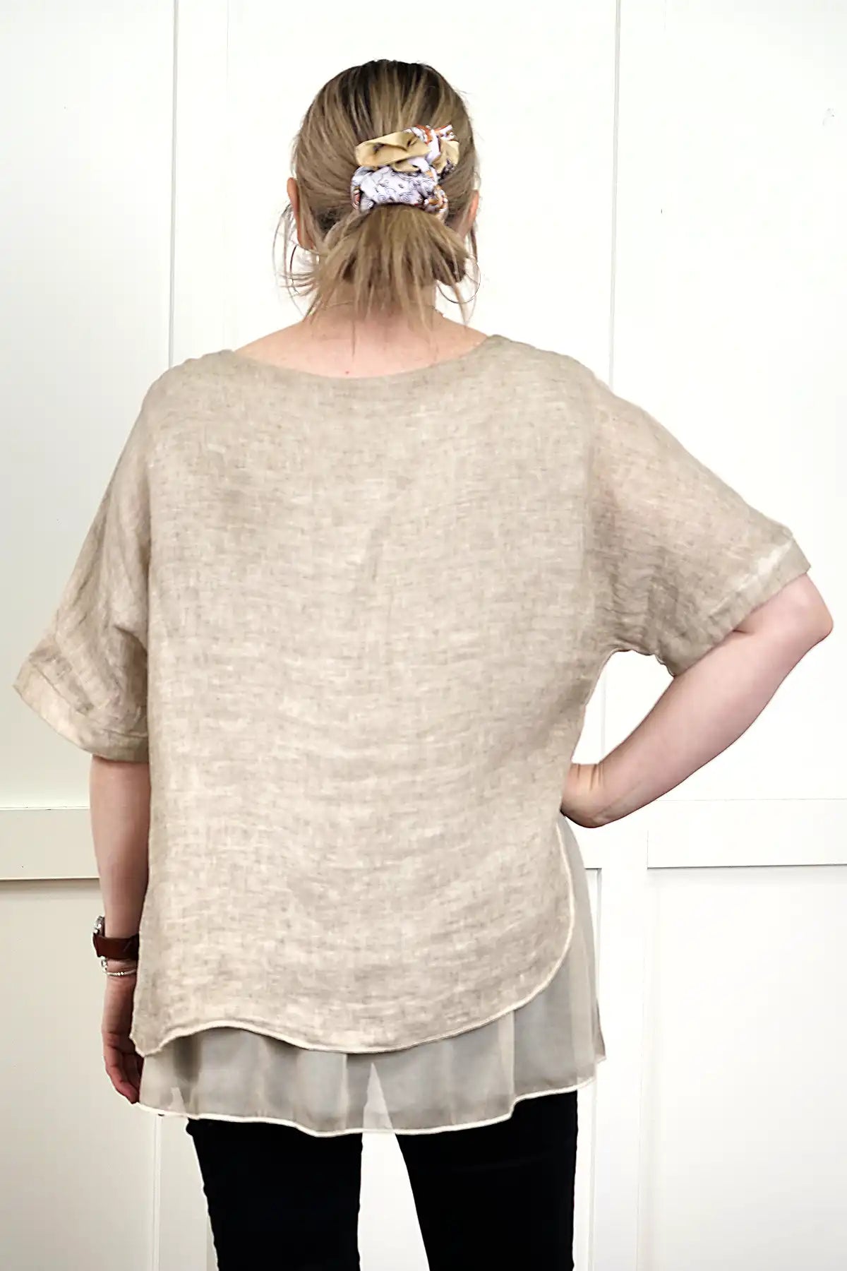 woman wearing the Elena Linen Top in Latte back view standing against a white wall