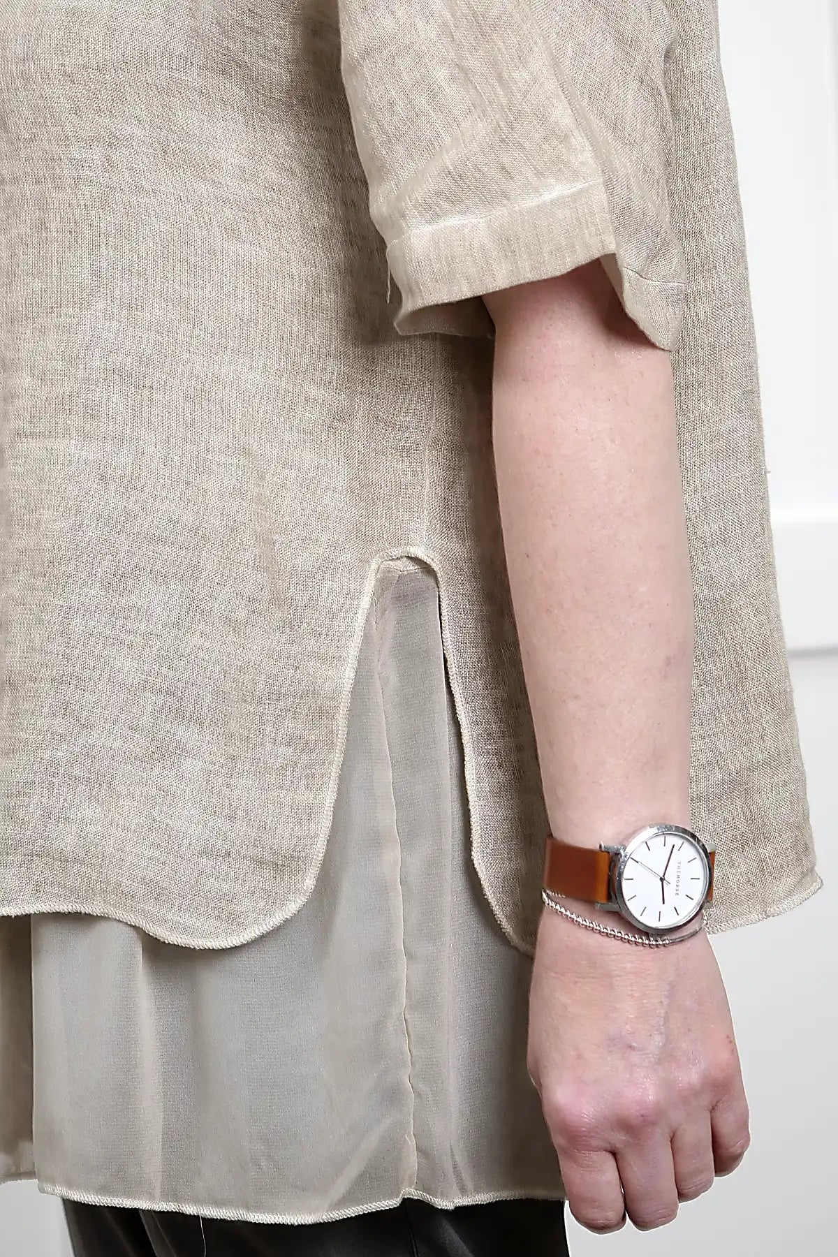 woman wearing the Elena Linen Top in Latte showing side split and layer detail standing against a white wall