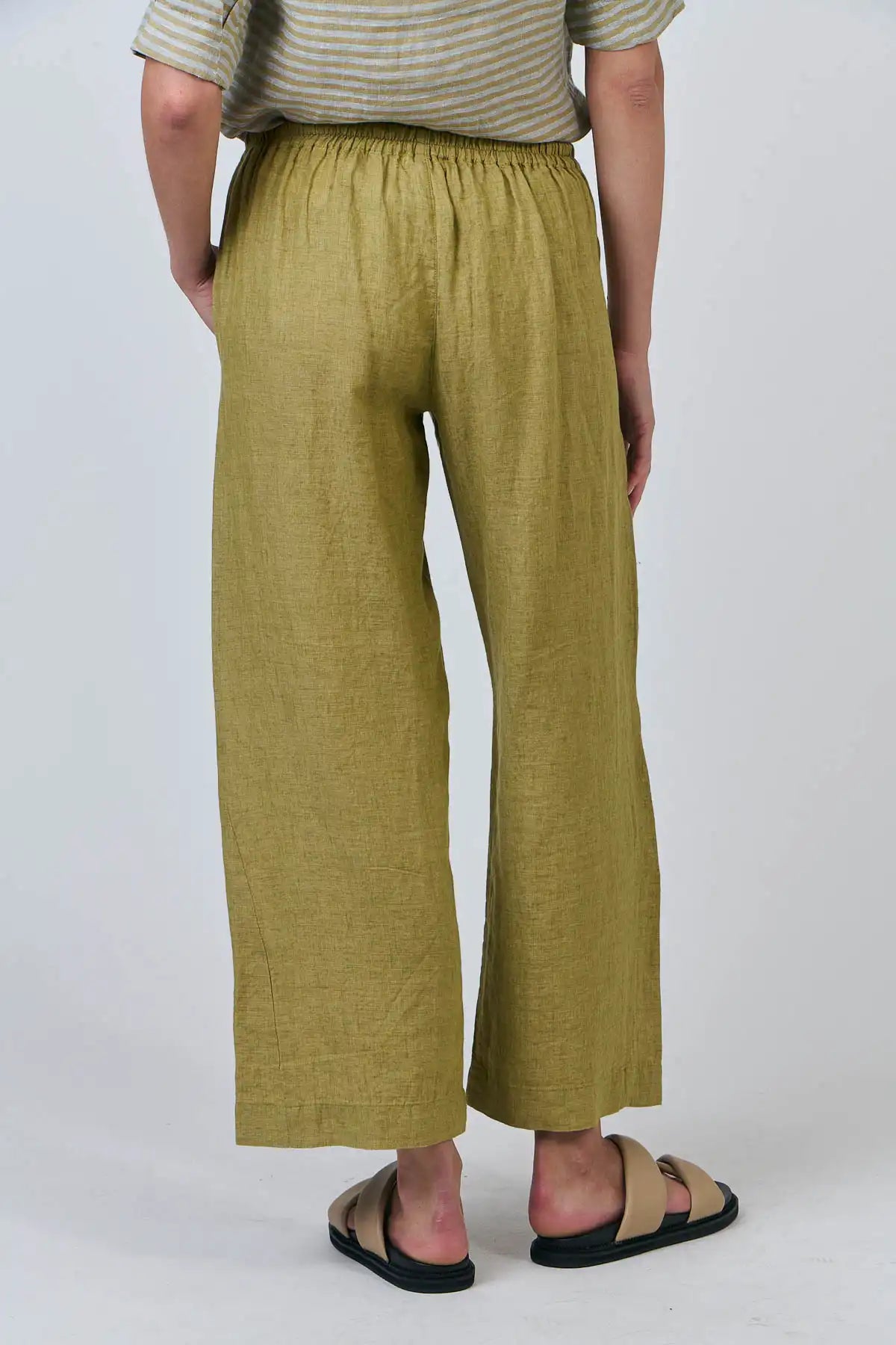 Person wearing Elysian Linen Pant in Bamboo Green on a plain background showing rear view of pant