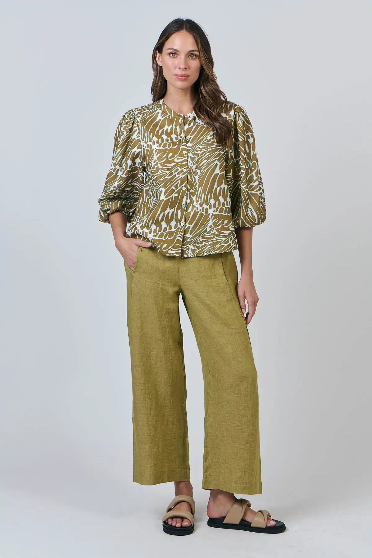 Woman wearing a patterned top and Elysian Linen Pant in Bamboo Green on a white background