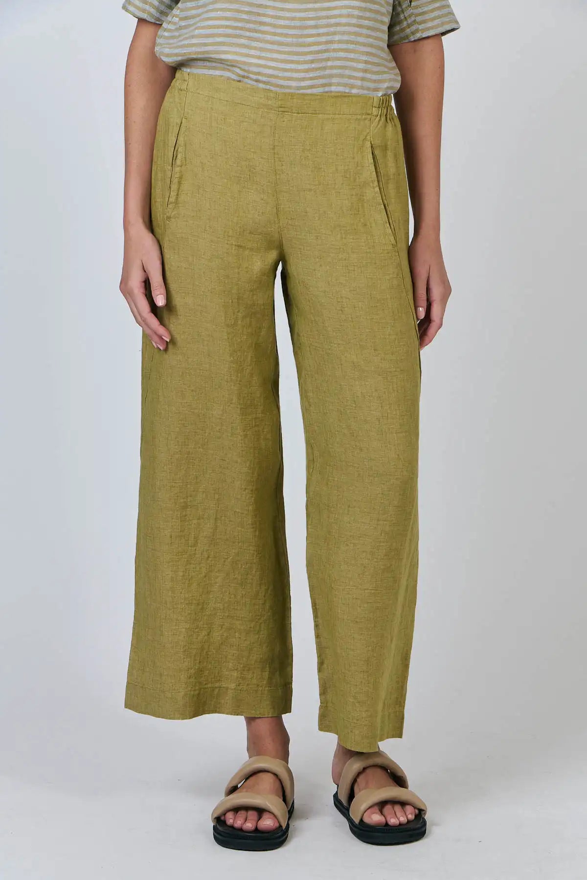 Person wearing Elysian Linen Pant in Bamboo Green and sandals on a white background front straight on view