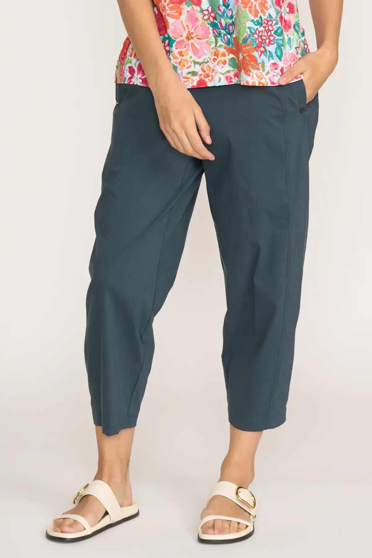 Person wearing Foil Gemini Pants in Basalt  and a colorful floral top on a plain background front detailed view