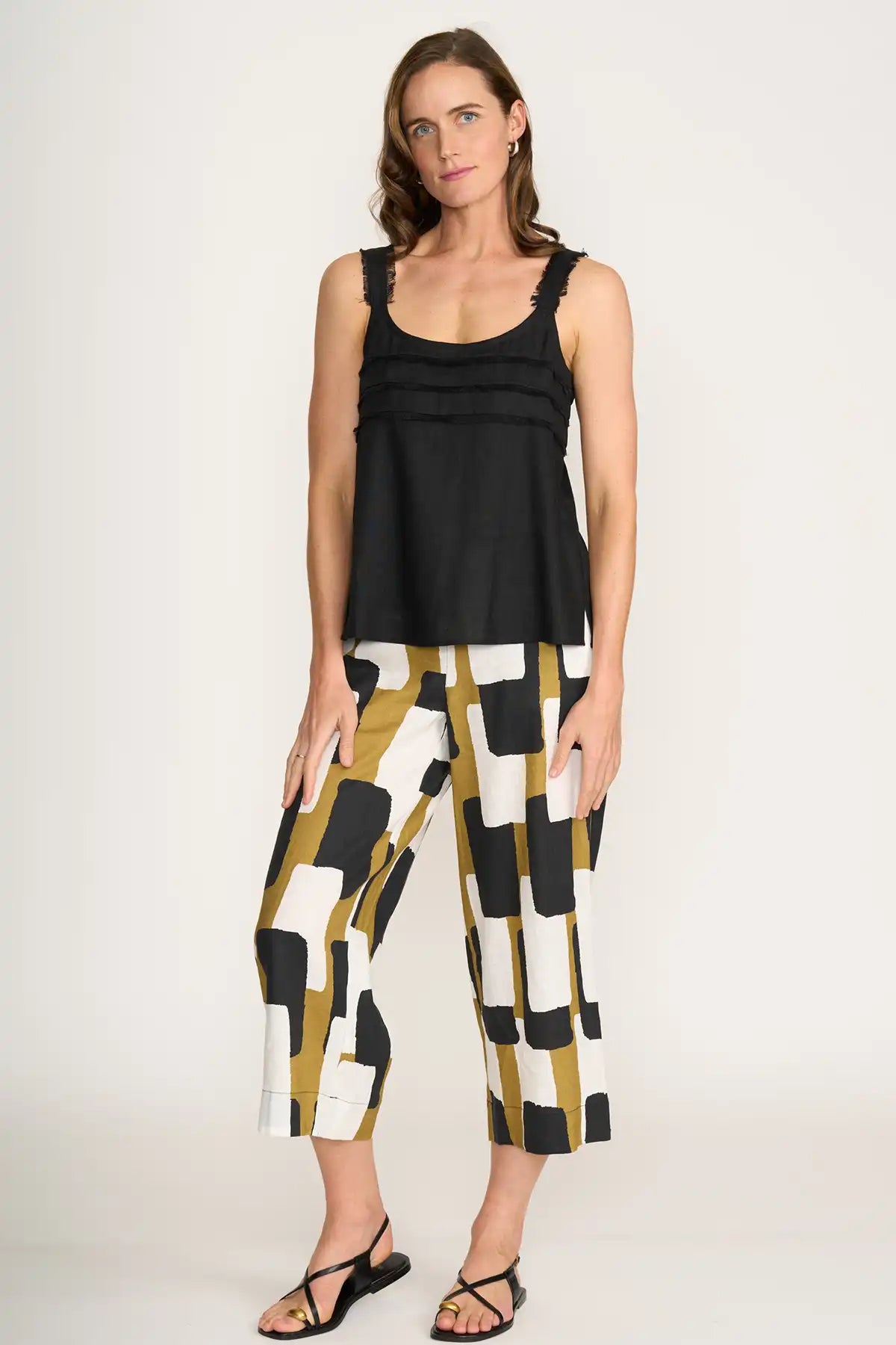Woman wearing a black sleeveless top and Foil It's Only Natural Linen Pants in Art Box Print on a white background side view