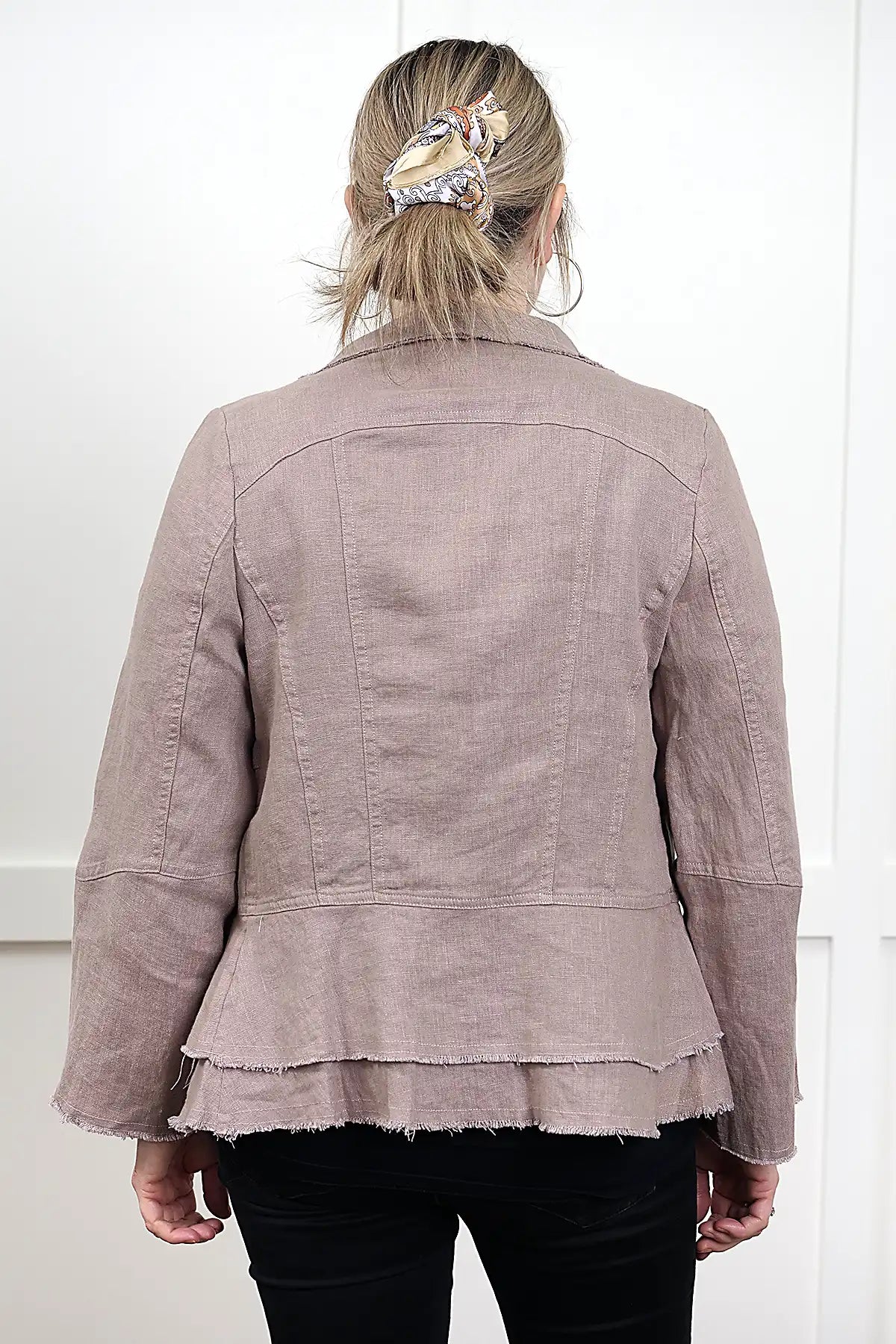woman wearing a Francesca Linen Jacket in Mushroom with black jeans with her back to the camera against a white wall