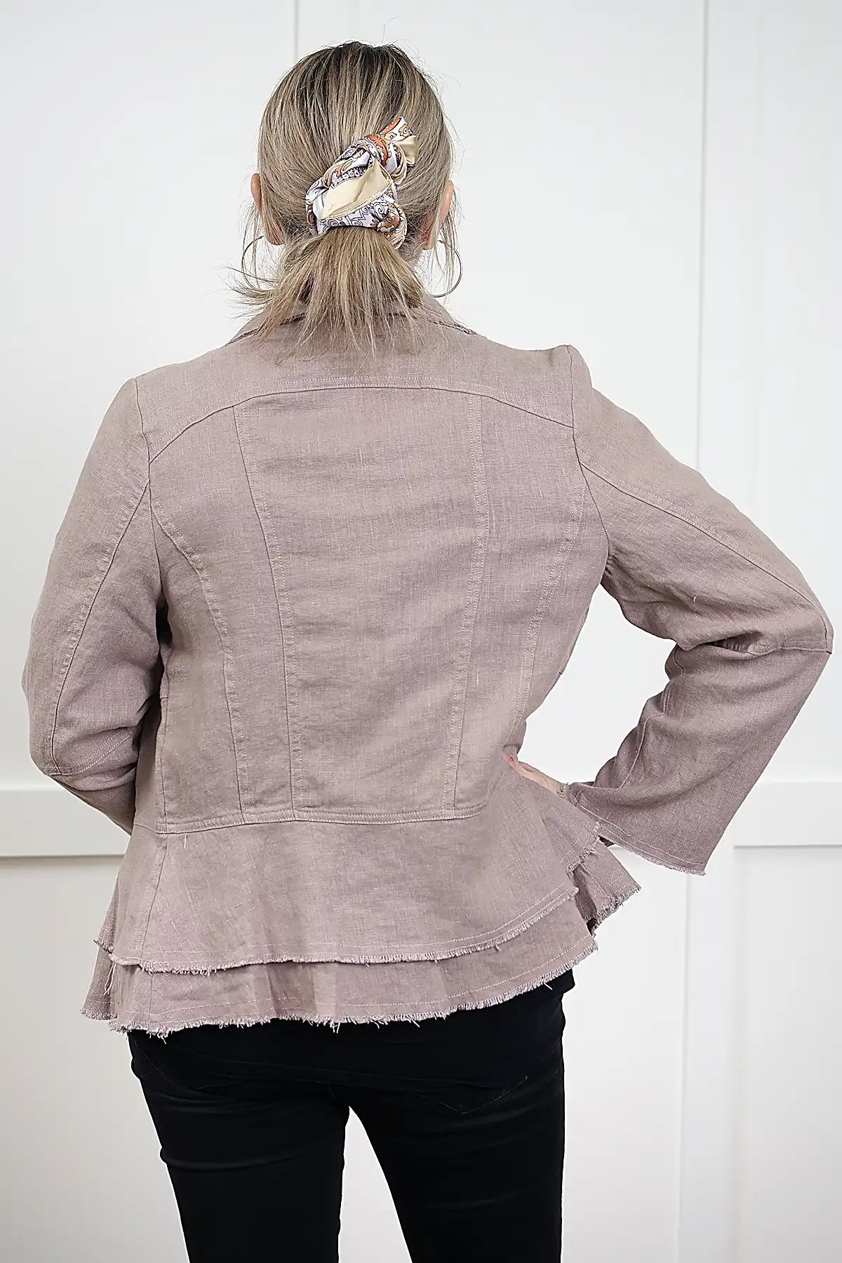 woman wearing a Francesca Linen Jacket in Mushroom with black tee and jeans with back to camera against a white wall
