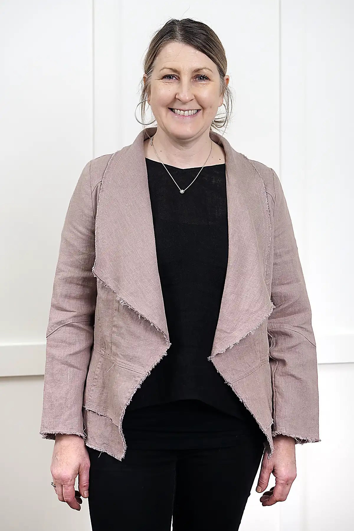 woman wearing a Francesca Linen Jacket in Mushroom with black tee and jeans against a white wall standing front on
