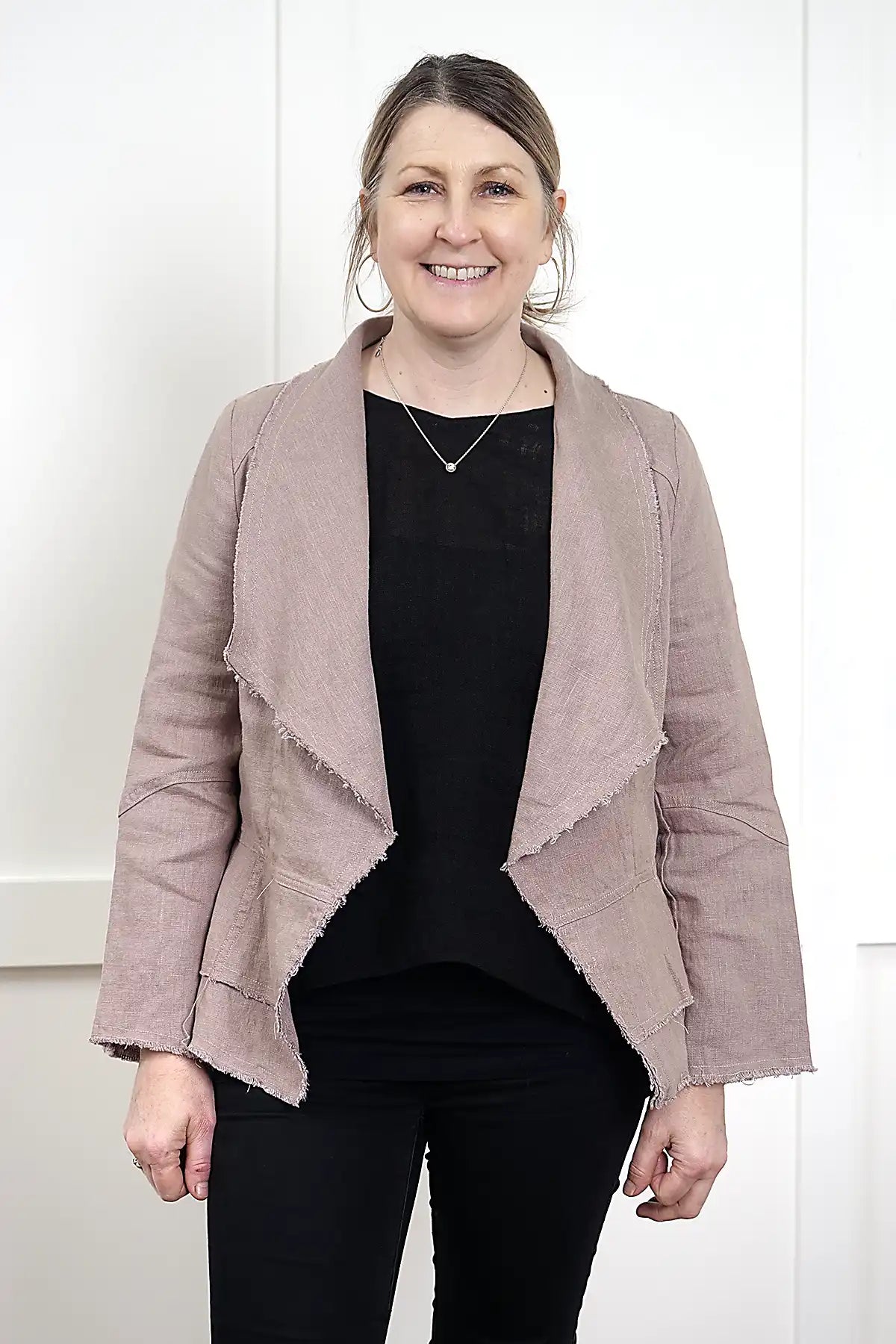 woman wearing a Francesca Linen Jacket in Mushroom with black tee and jeans against a white wall standing front on