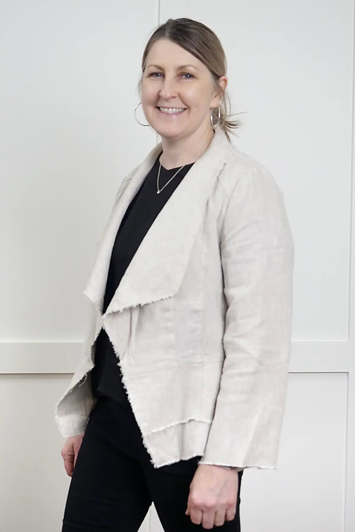 woman wearing the Francesca Linen Jacket in Natural standing 3/4 on against a white wall