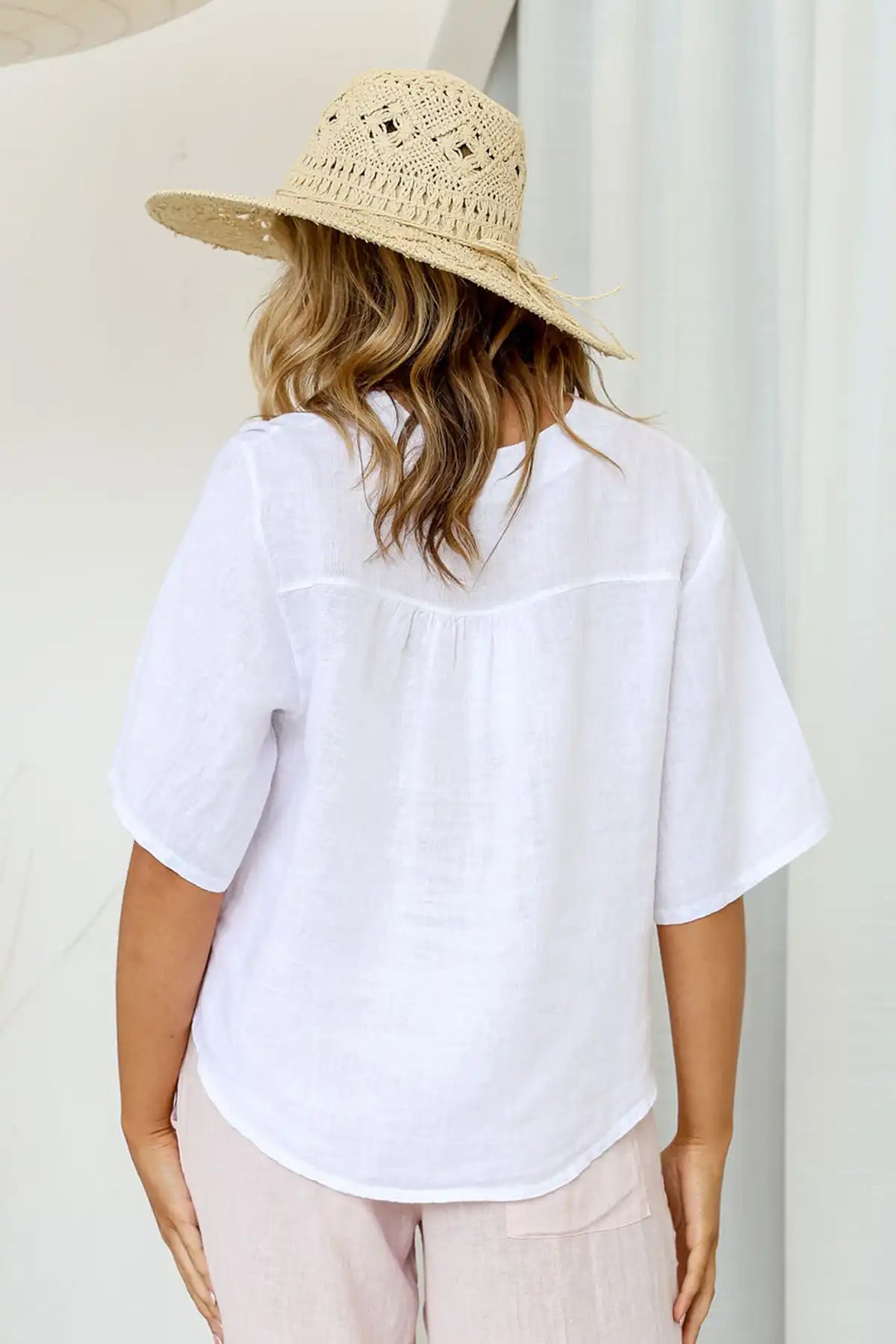 Person wearing a Gemma Italian Linen White Top and straw hat against a neutral background back view