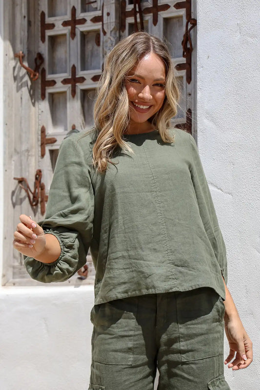 Woman wearing an Giovanna Italian Linen Top in Juniper standing in front of a textured wall.
