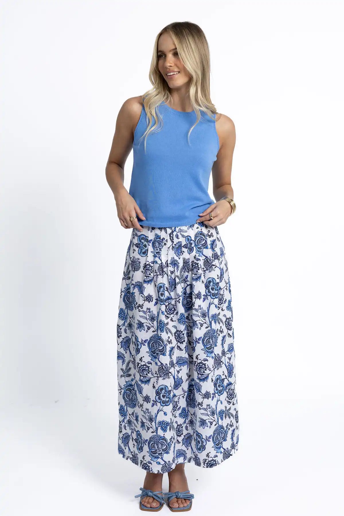 Woman wearing a Humidity Collette Tank in Cornflower Blue and floral pants on a white background