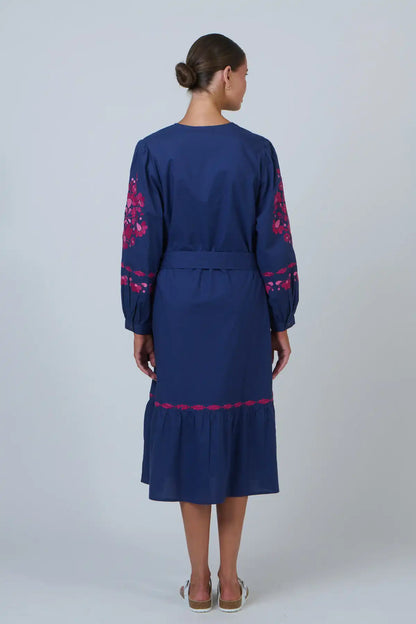 woman wearing Ink Rose Embroidered Midi Dress and white sandals staning back on against a white background
