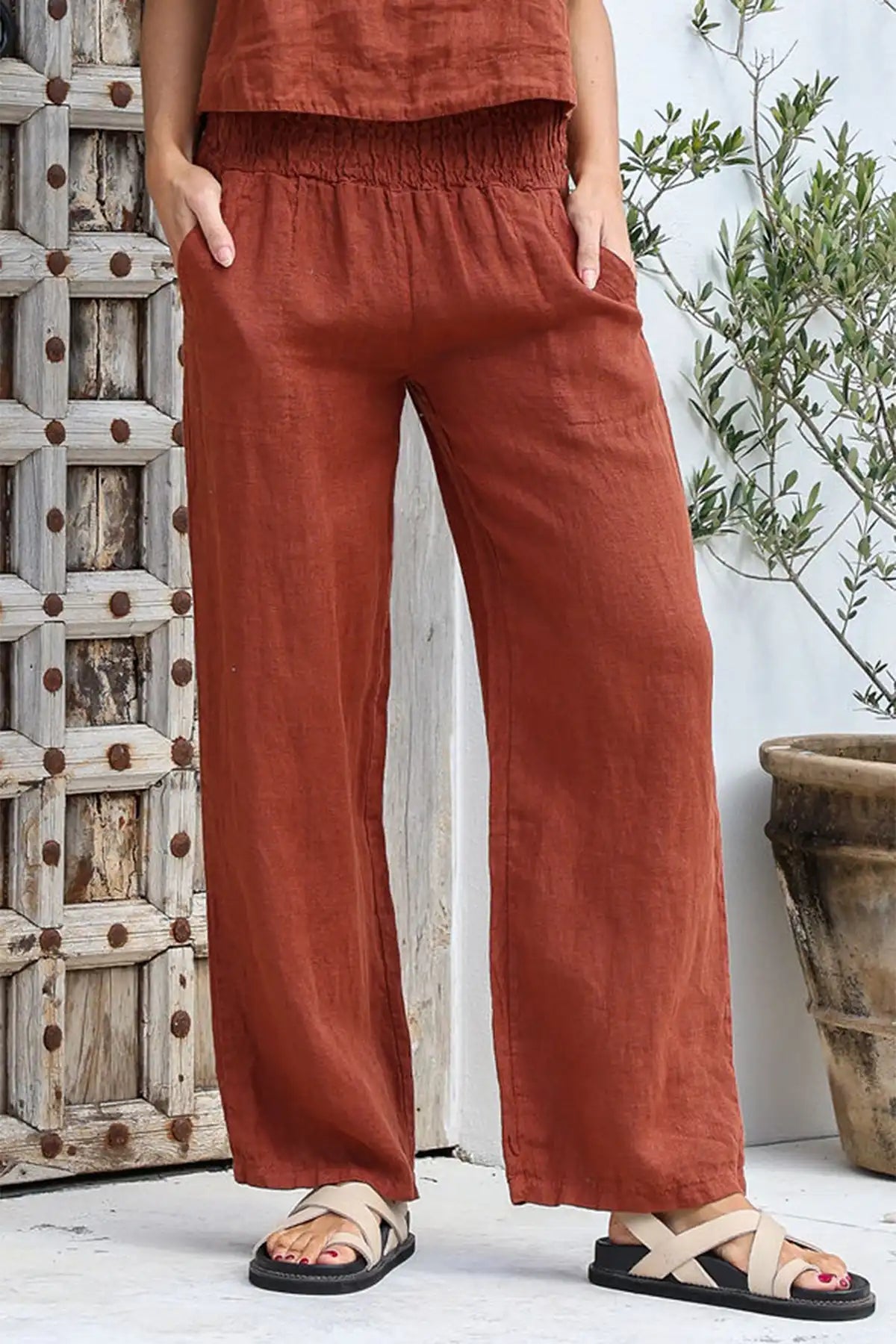 Person wearing Isabella Italian Linen Pant in Coco standing against a wooden wall with a plant in the background