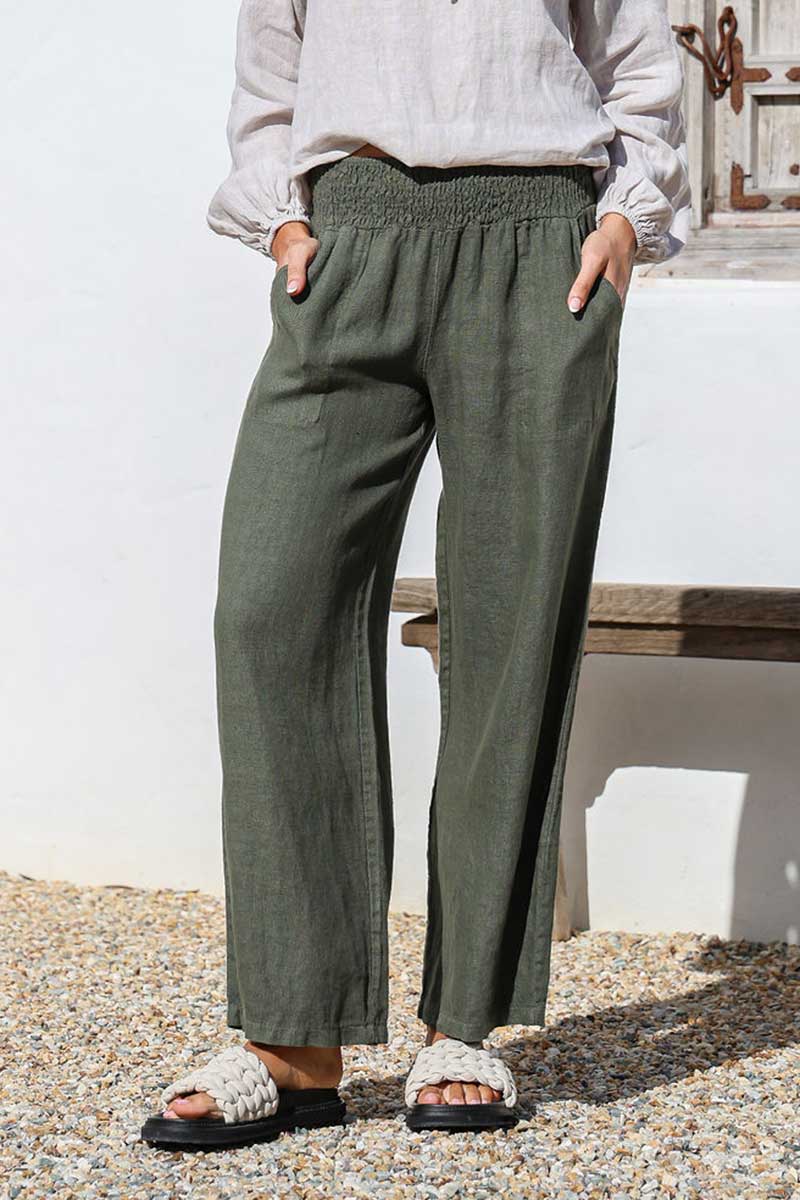 lady wearing juniper green linen pants with elastic waist and sandas outside in courtyard
