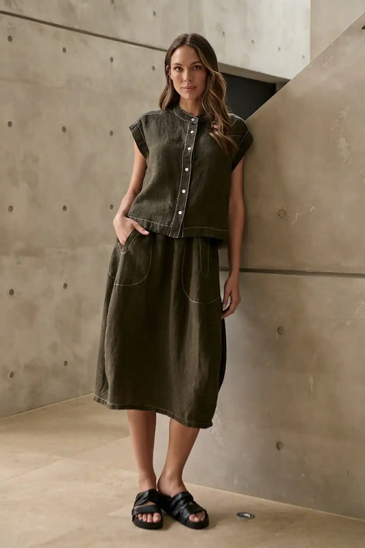 Woman wearing a Licorice Linen Skirt standing against a concrete wall.