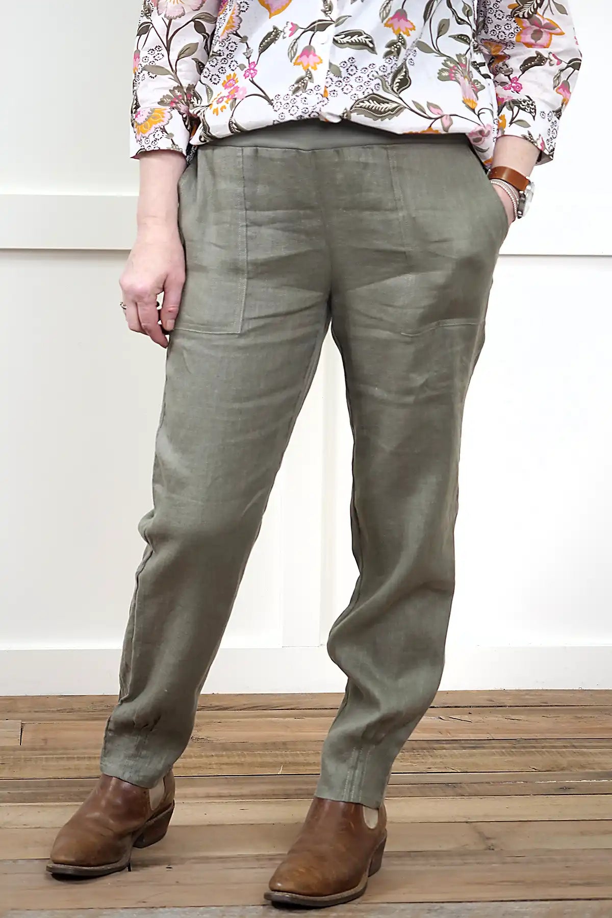 Person wearing Lina Linen Pull-On Pants in Olive and a floral blouse on a wooden floor.