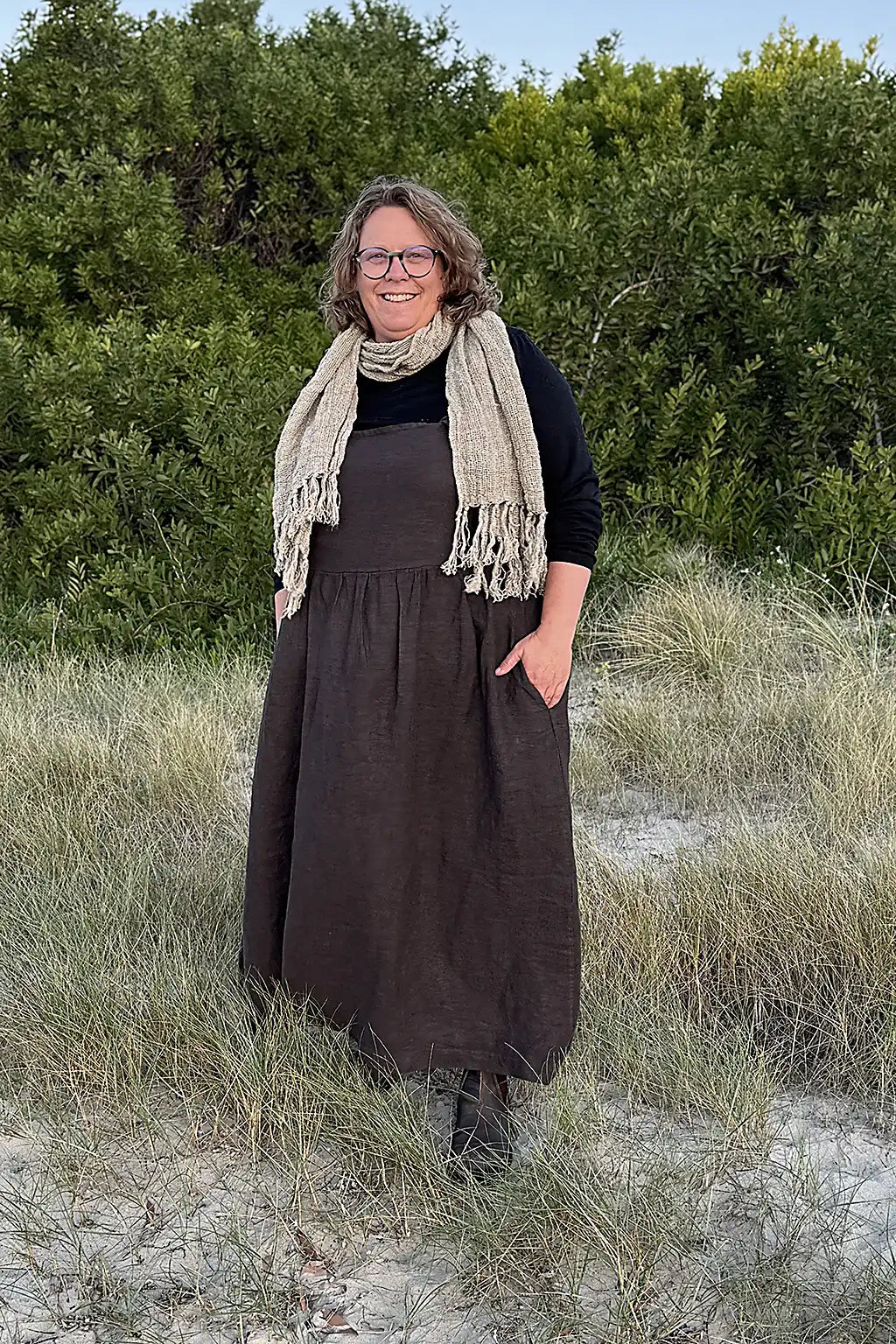 women standing at beach wearing a linen pinafore and linen scarf in natural colours
