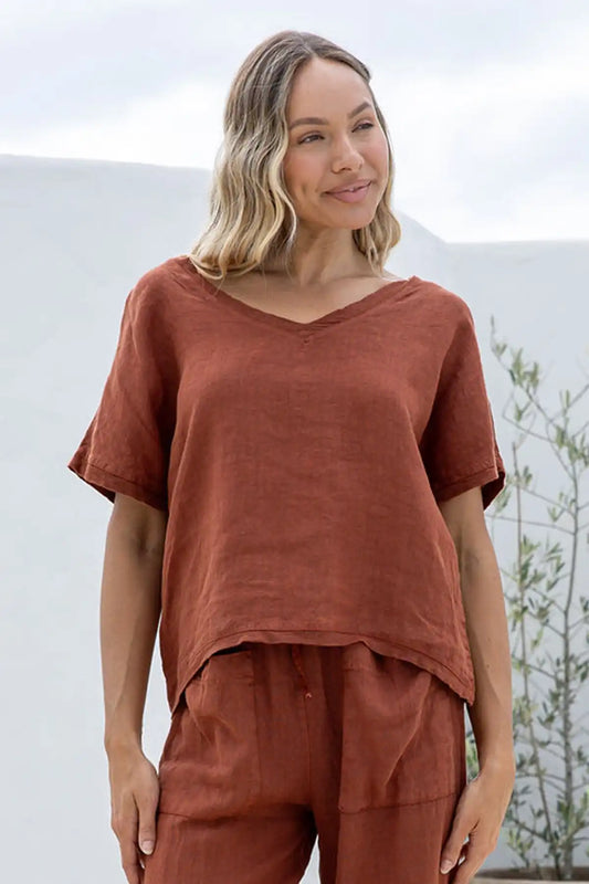 Woman wearing a Lucia Italian Linen Coco Top and pants standing outdoors with a blurred background
