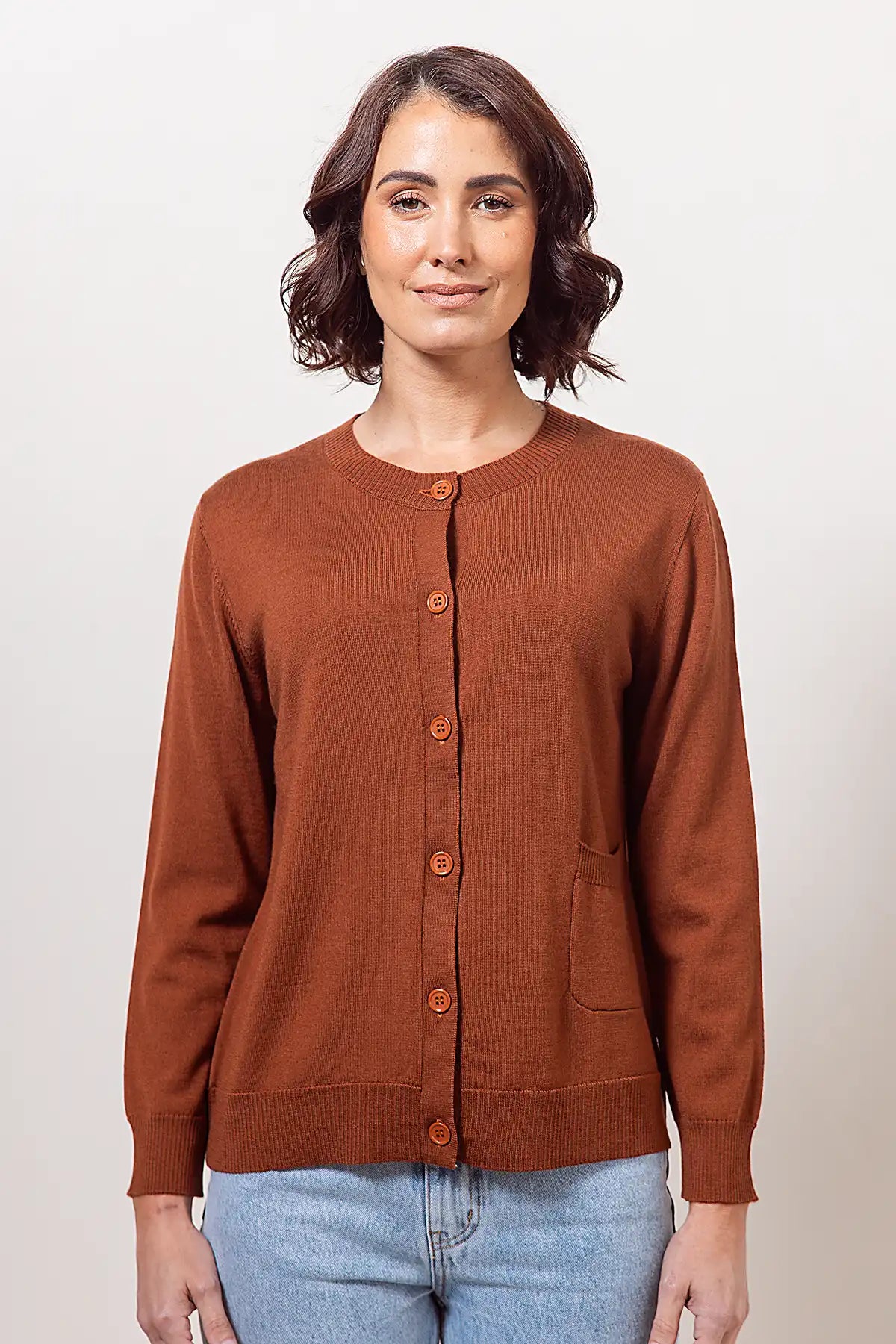 Woman wearing a copper merino cardigan against a plain background