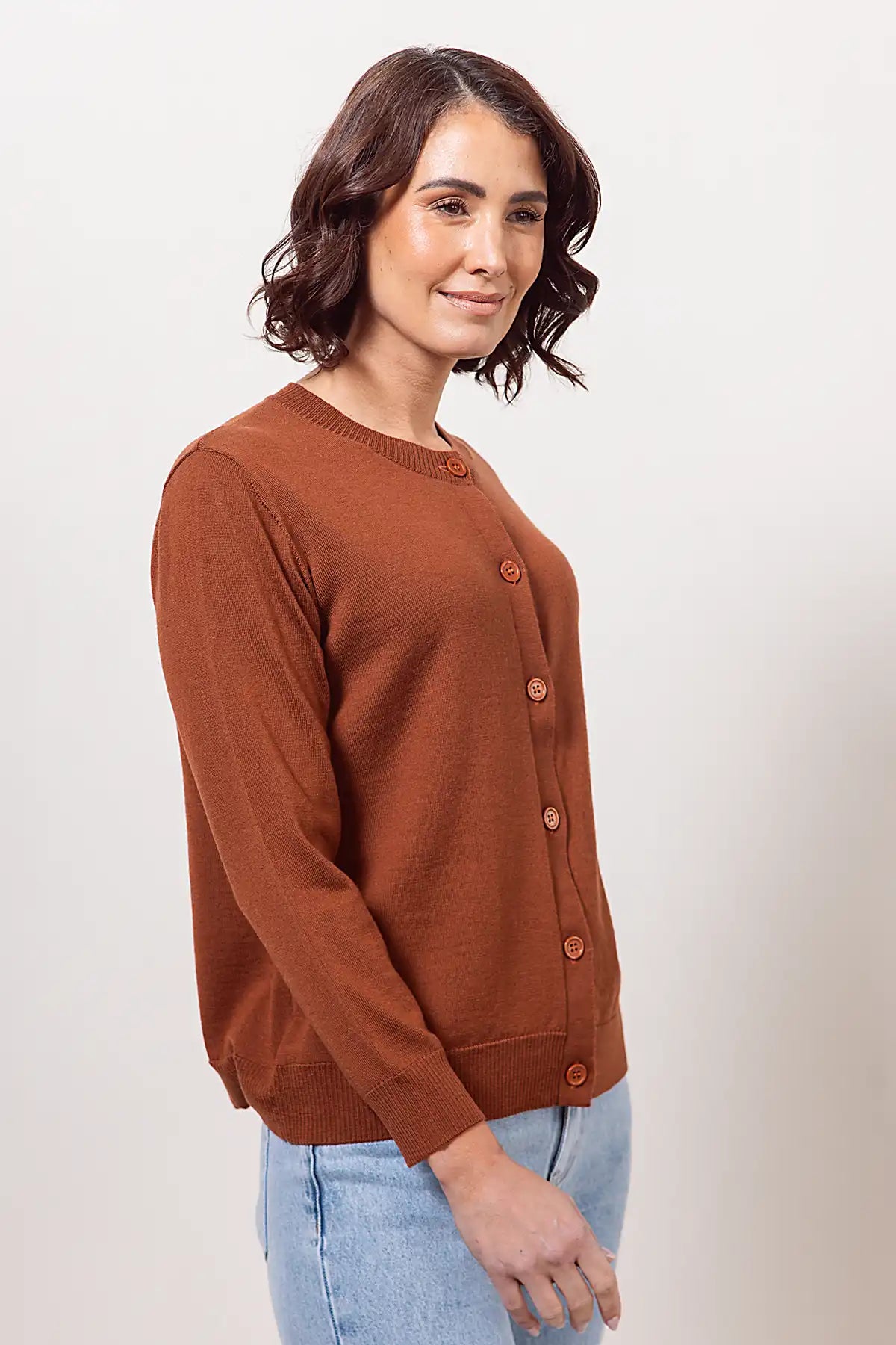 Woman wearing a woolen copper cardigan against a plain background
