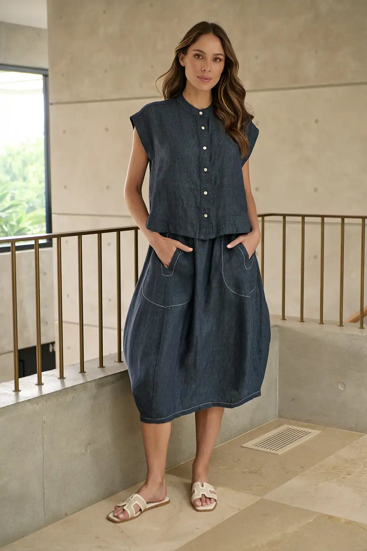 Woman wearing a blue sleeveless top and Bay Blue Linen Skirt standing indoors with a neutral background