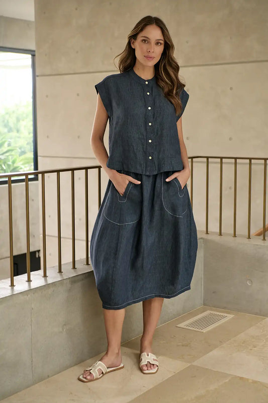 Woman wearing a blue sleeveless top and Bay Blue Linen Skirt standing indoors with a neutral background