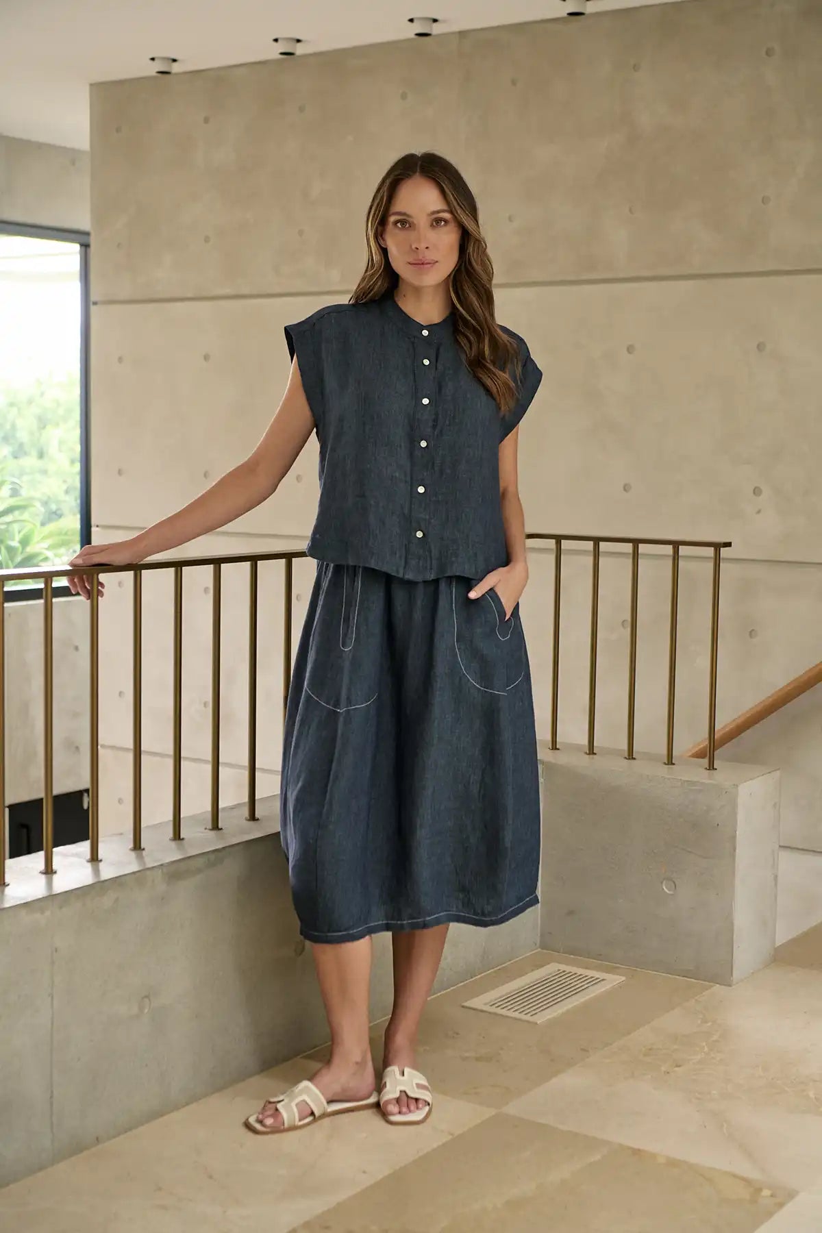 Woman in a Bay Blue Linen Skirt and top standing on a staircase with a neutral background
