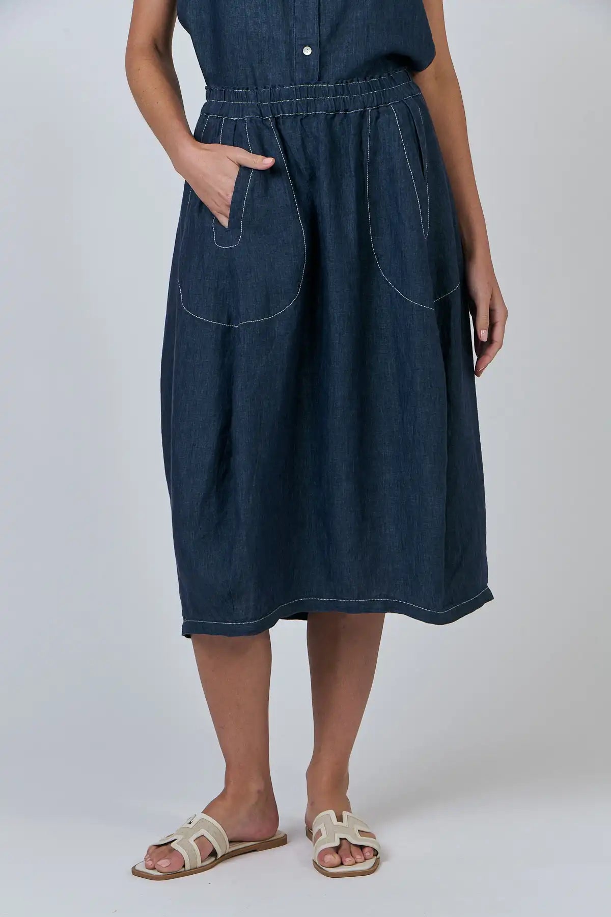 Person wearing a Bay Blue Linen Skirt on a white background front view with one hand in the pocket