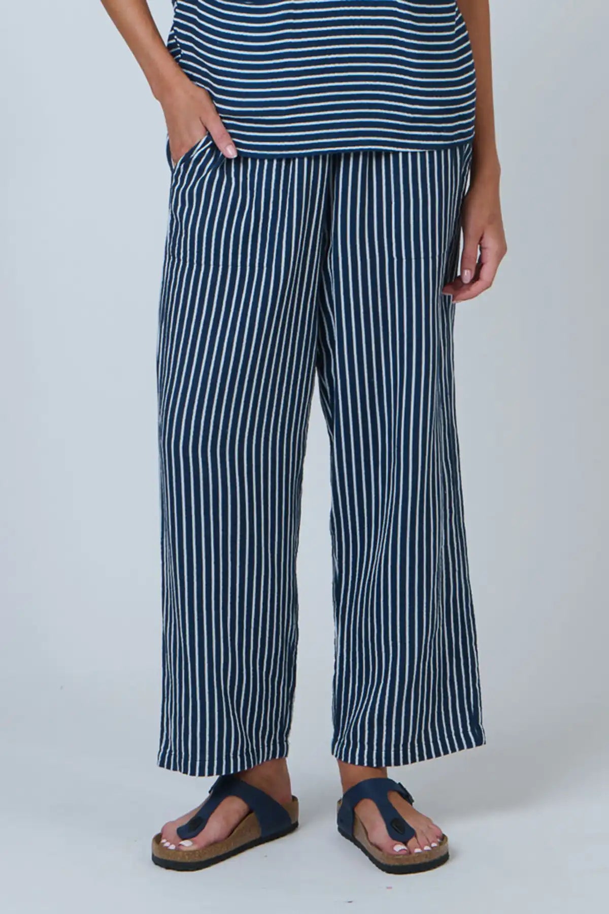 Person wearing blue and white striped top and pants on a plain background