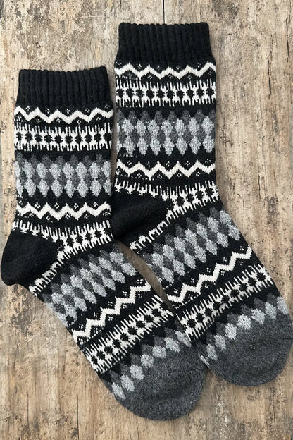 Pair of black, gray, and white patterned socks on a wooden surface