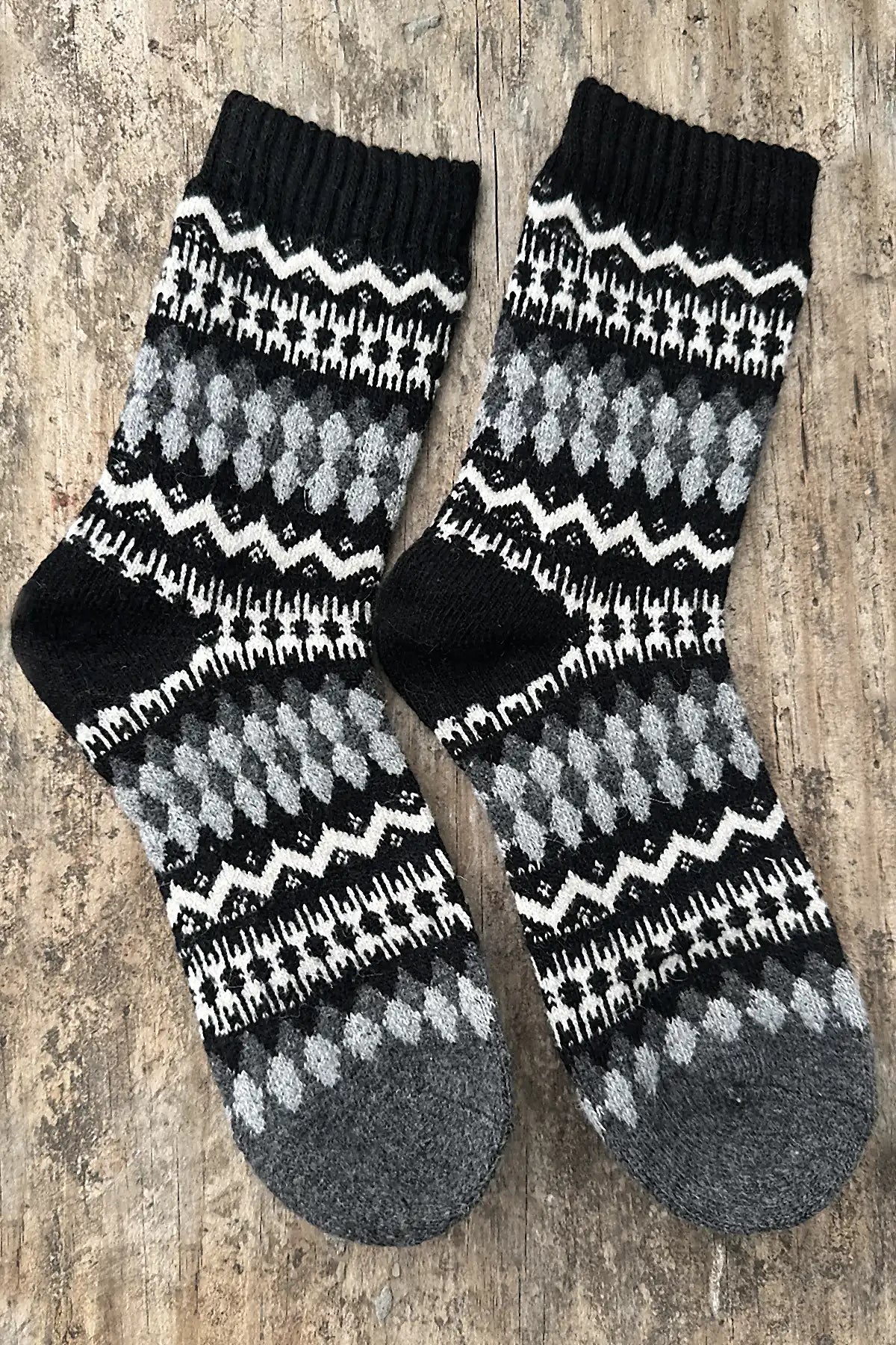 Pair of black, gray, and white patterned socks on a wooden surface