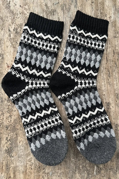 Pair of black, gray, and white patterned socks on a wooden surface