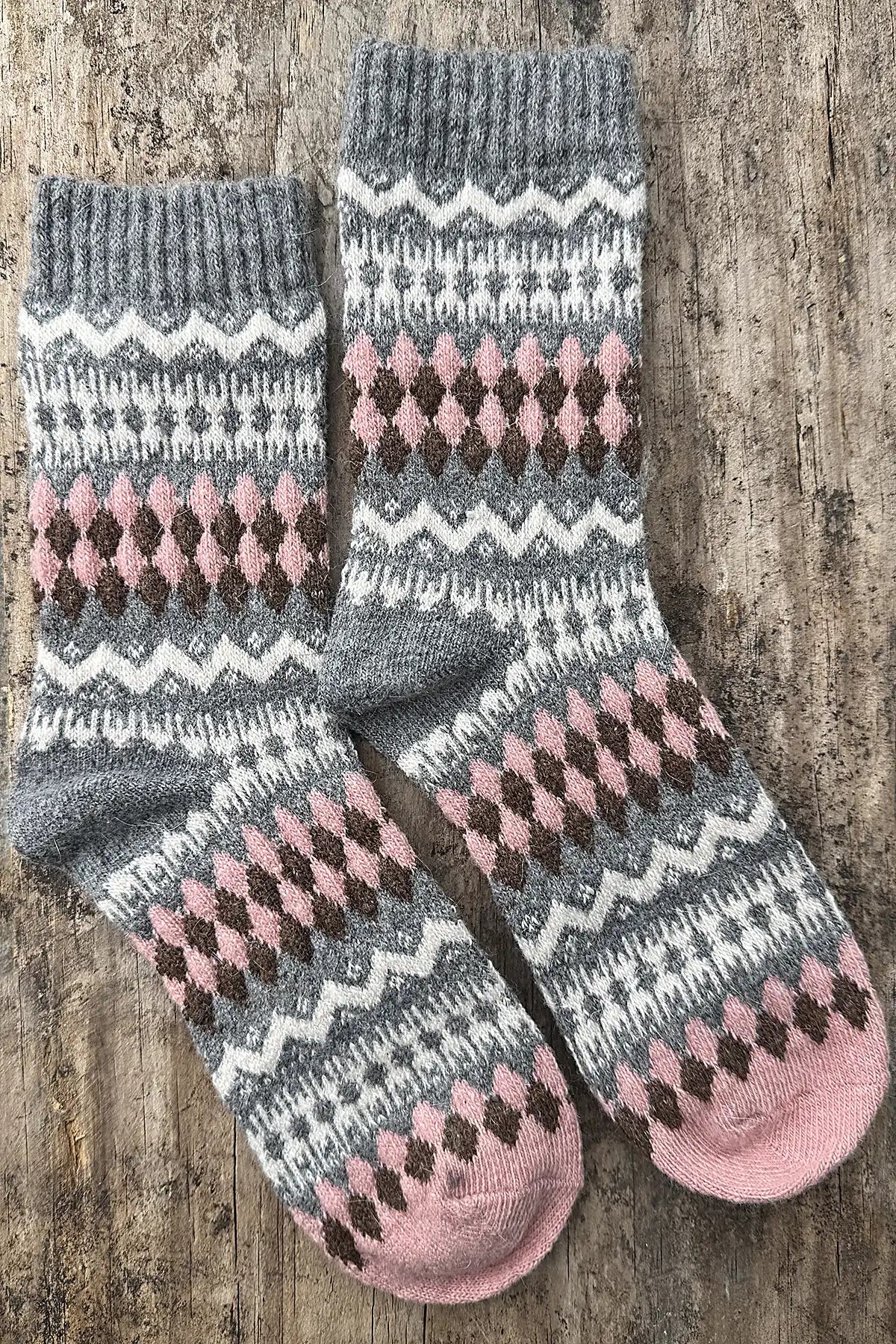 Pair of gray and pink patterned socks on a wooden surface